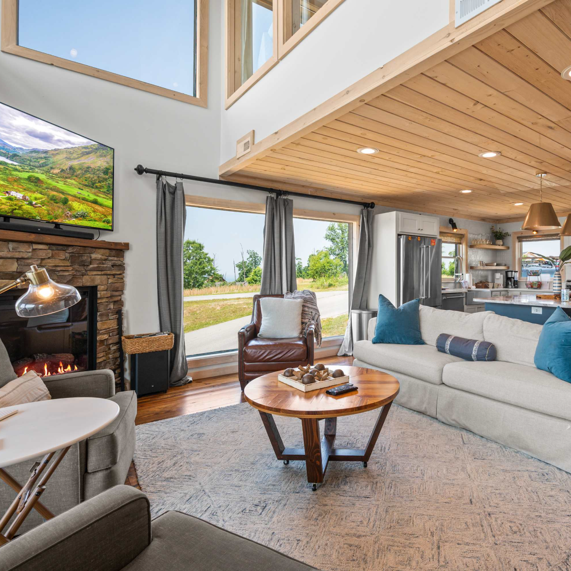 Den of a Sevierville cabin, with a television, fireplace, sitting area, and a connected kitchen